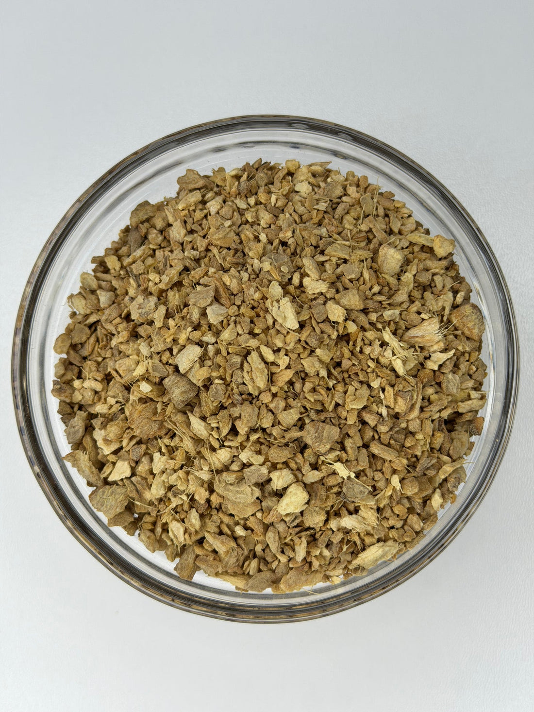Dried ginger root, cut and sifted, in a glass bowl