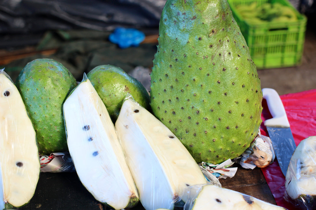 Soursop fruit, whole and cut open to show the white pulp
