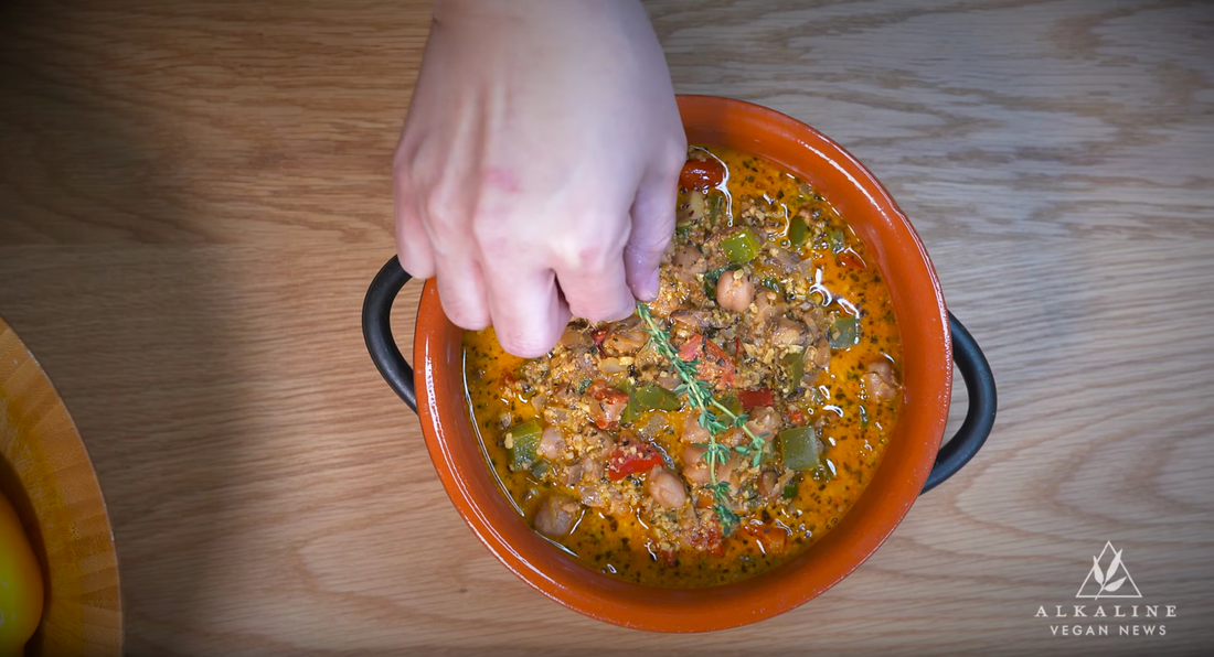 vegan chili in a pot on wooden table with sprig of fresh thyme