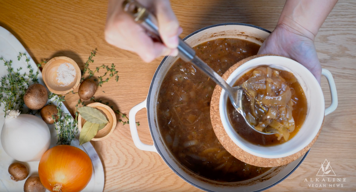 french onion soup in pot with vegetables on wooden table