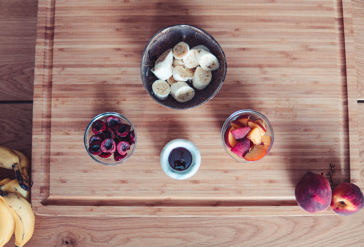 Fresh fruits in bowls on a wooden cutting board